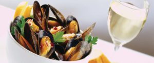 Mussels in a bowl with a glass of white wine